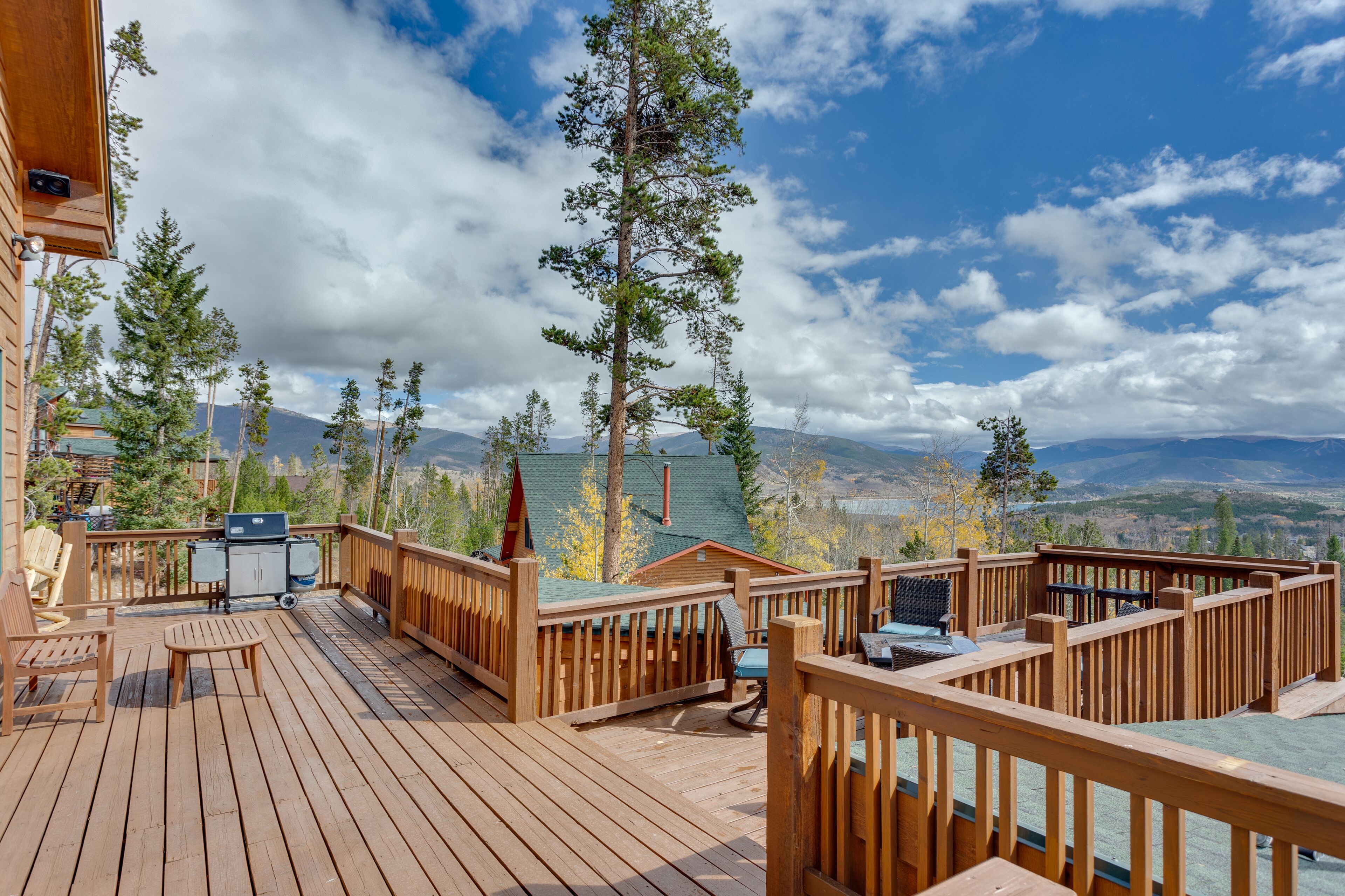 A wooden deck with outdoor seating, a grill, and a view of mountains.