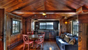 A cabin interior with a dining area, kitchen, and a sofa. - Hood Canal, 1930's Beach Cottage,  315' Cove with Oysters! (Hoodsport)