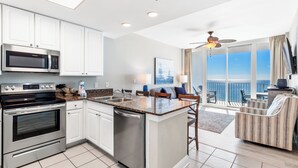 A modern kitchen with stainless steel appliances, a large island, and a view of the ocean through the balcony. - Newly Updated Direct Gulf View 1BR & Bunkroom/2Bath (Gulf Shores)