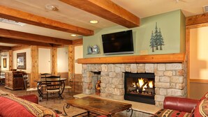 A cozy living room with a stone fireplace, leather sofas, and a wooden coffee table. - Fantastic Studio Condo Near the Lifts (Dillon)