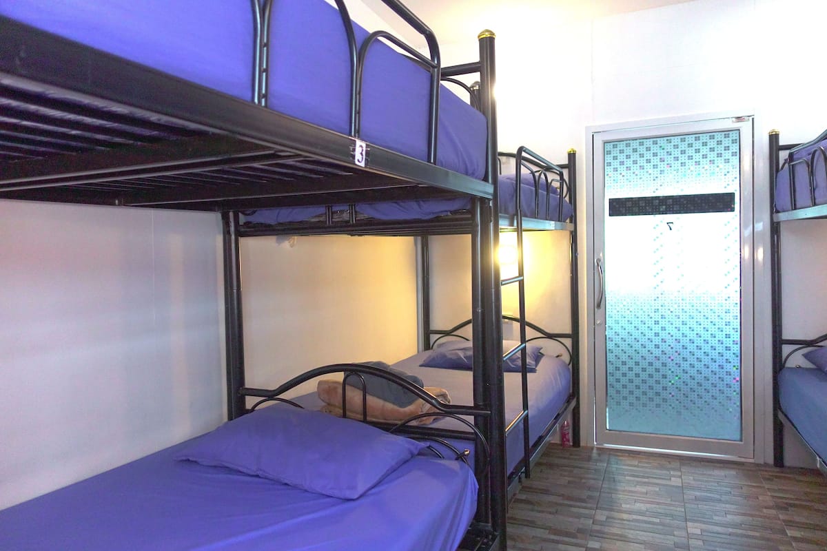 A dormitory room with bunk beds, a door with frosted glass, and a wooden floor.