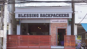 A storefront named "Blessing Backpackers" with a red bench in front. - Blessing Backpackers (Ko Pha-ngan)