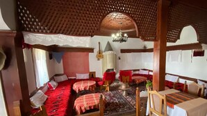 A traditional inn with wooden furniture, a red carpeted floor, and a lattice ceiling. - Rooms Merlika (Krujë)