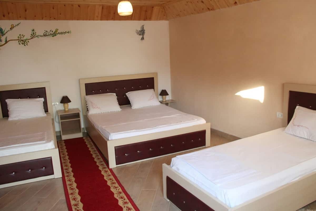A bedroom with two beds, a red carpet, and a wooden ceiling.