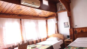 A room with two beds, wooden beams, a window with curtains, and a wall-mounted heater. - Rooms Merlika (Krujë)