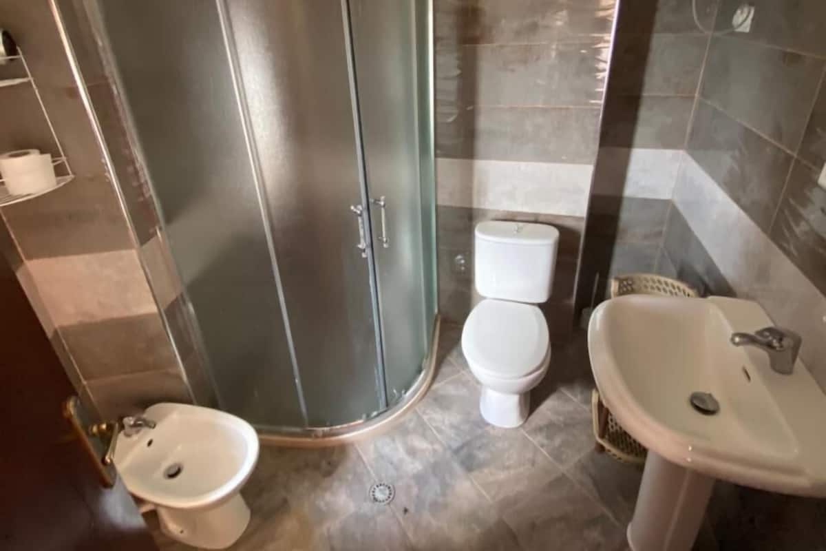 A bathroom with a shower enclosure, a toilet, and a sink.