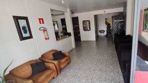 Ein Empfangsbereich mit einer Couch, einem Kühlschrank, einem Feuerlöscher und einem Spiegel an der Wand.