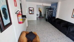 Eine Hotellobby mit Feuerlöscher, Weihnachtstannenbaum, Kühlschrank und einer Reihe schwarzer Sofas.