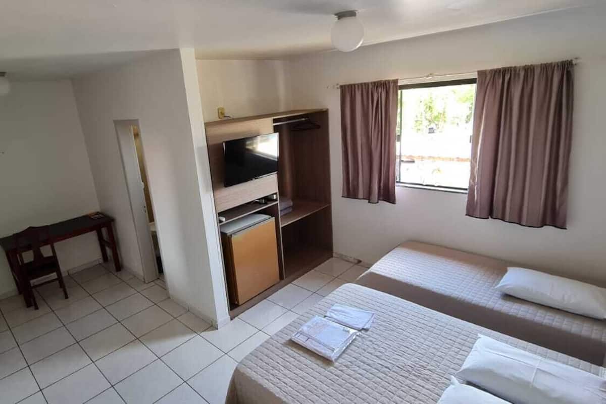 A compact hotel room with a bed, a desk, a television, and a wardrobe.