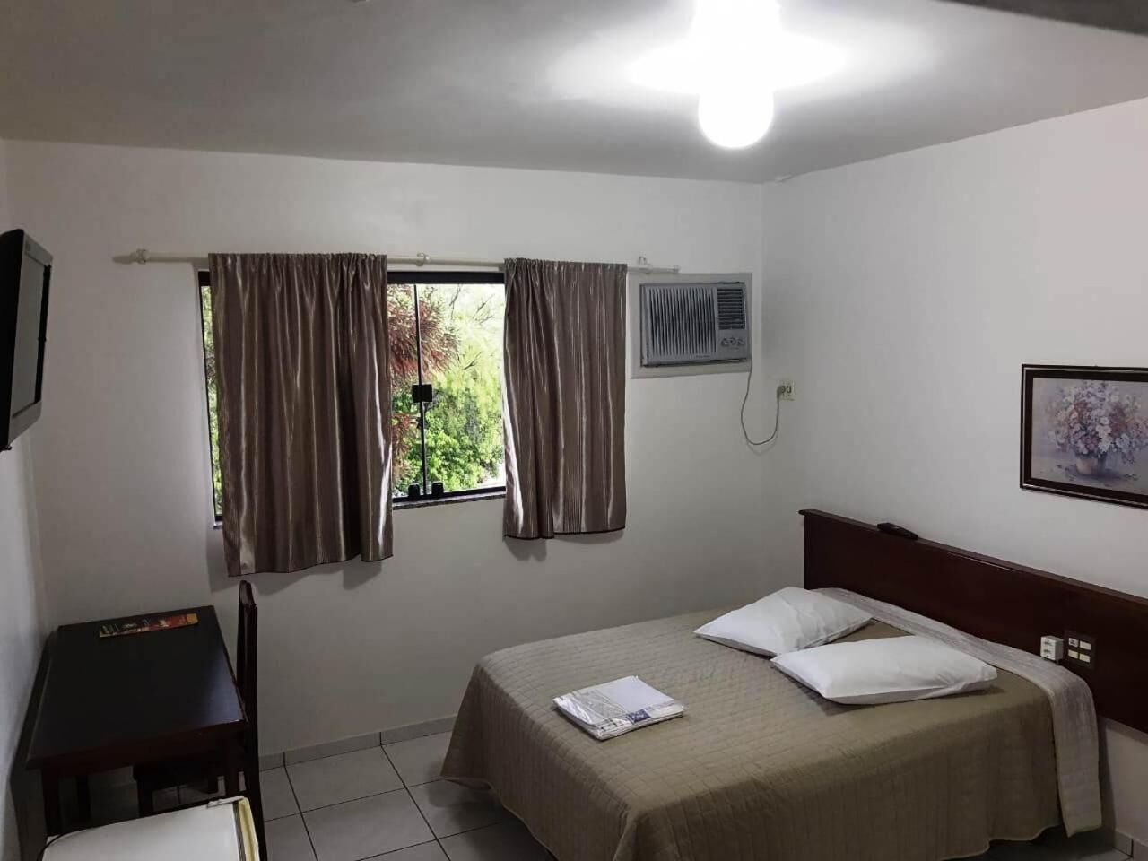 A small, clean room with a bed, a desk, and a window with curtains.