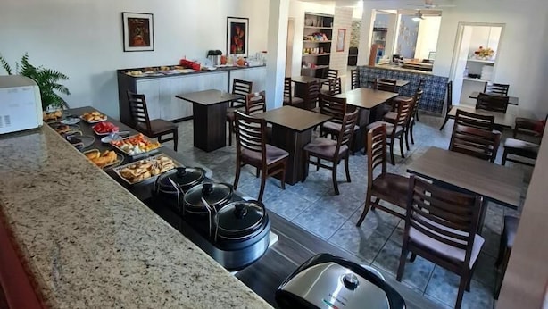 Ein geräumiger Essbereich mit mehreren Tischen und Stühlen, eine Küchenzeile mit Herd und Spüle sowie eine Sitzecke mit Sofa und Couchtisch.