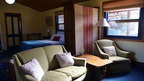 A cozy room with a bed, two armchairs, a table, and a window with blinds. - Relax in a beautiful private peaceful setting 5 minute drive from Beechworth (Wooragee)