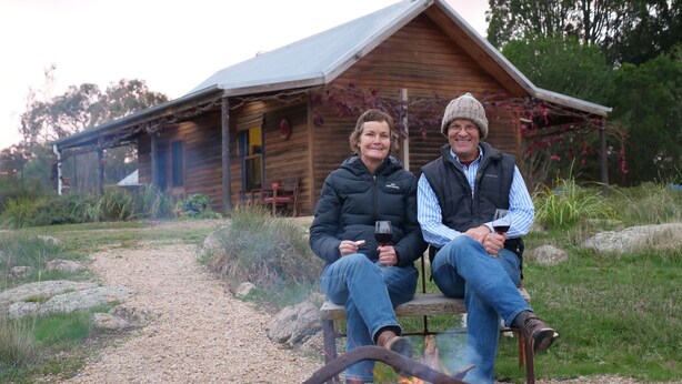 Two people sitting on a bench outside a wooden cabin with a gravel path and greenery in the background. - Relax in a beautiful private peaceful setting 5 minute drive from Beechworth (Wooragee)
