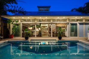 Una casa moderna con piscina, ampie finestre e una veranda coperta.
