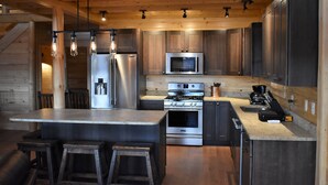 Una cucina moderna con elettrodomestici in acciaio inossidabile, mobili in legno e un'isola centrale con sgabelli.