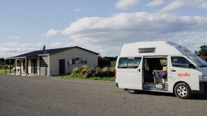Ein weißer Van mit der Aufschrift "apollo" ist vor einem kleinen Gebäude mit einer Veranda geparkt.