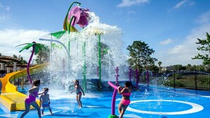 Een waterpark met diverse waterattracties, waaronder een grote fontein en glijbanen.