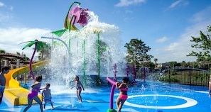 Een waterpark met diverse waterattracties, waaronder een grote fontein en glijbanen.