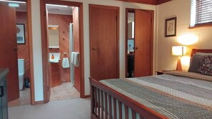 Ein Schlafzimmer mit einem Bett, einem Nachttisch, einer Lampe und einem Fenster mit Jalousien.