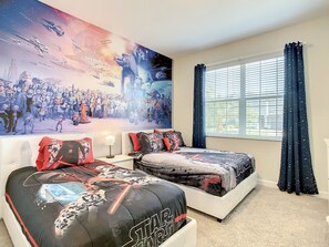A bedroom with Star Wars-themed bedding, a large wall mural, and a window with curtains. - 🏝️ 5BR/5BA Home w/ Private Pool & Spa, Themed Kids’ Rooms & Resort Fun | Storey Lake Near Disney (Kissimmee)