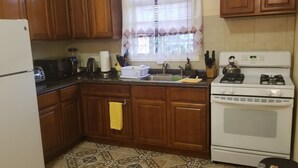 A kitchen with wooden cabinets, a white refrigerator, a stove, and a sink. - Paradise on the Isle of Spice (Calivigny)