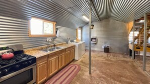 A compact kitchen with a stove, sink, and a washing machine. - W-W: The Barndominium for Large Groups (Monticello)