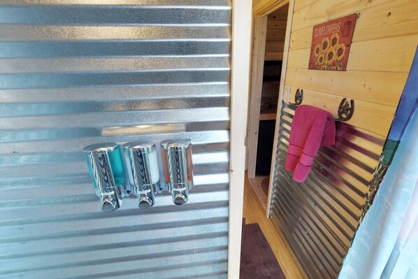 A metal door with four glass containers on the left and a wooden door with a towel rack on the right.