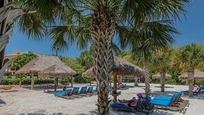 A beach with thatched umbrellas, sun loungers, and palm trees. - Family Friendly Bahama Bay Condo near Disney (Davenport)