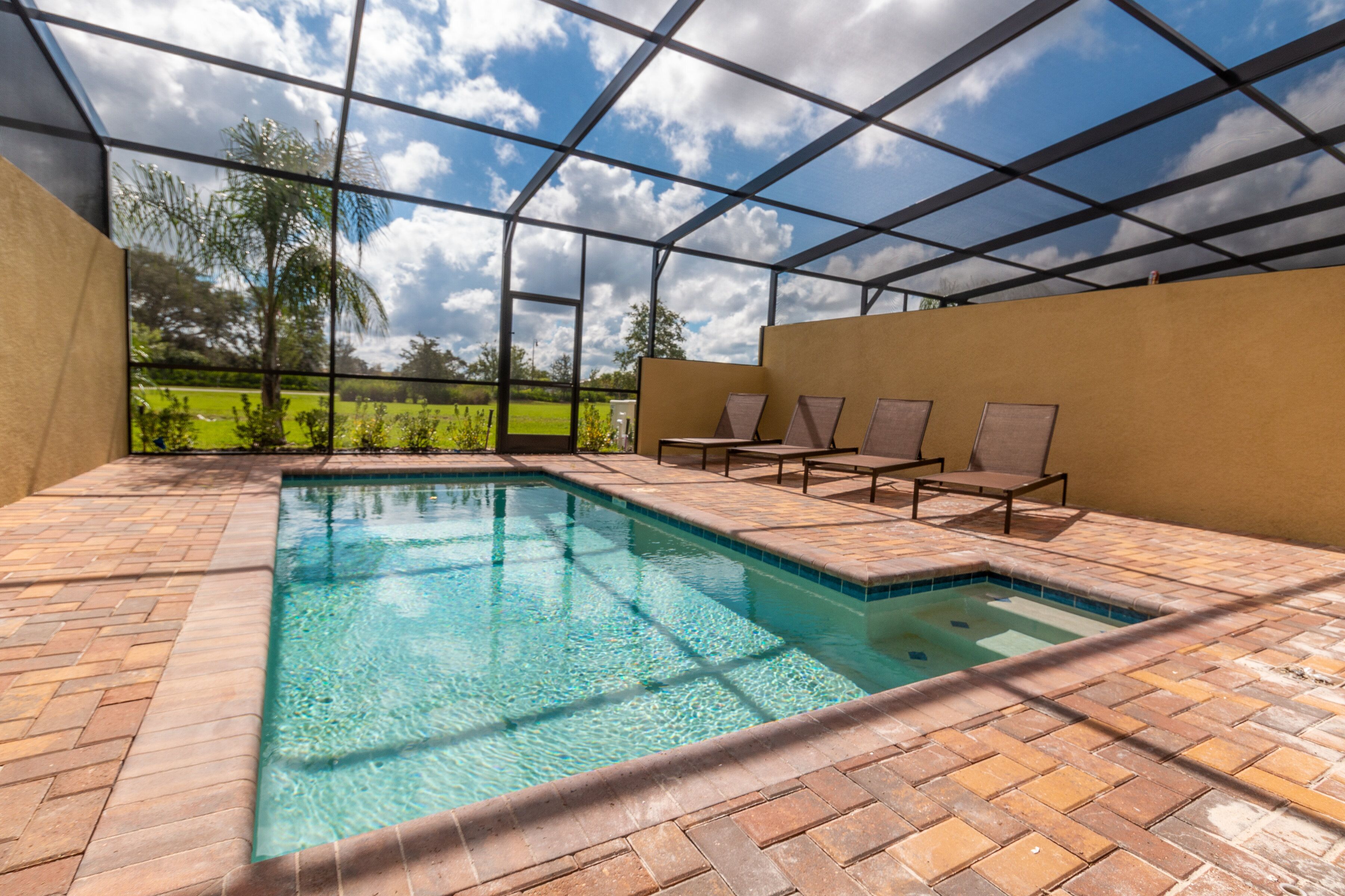 A swimming pool with a tiled edge, surrounded by lounge chairs and a covered area with a metal frame.