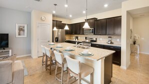 A modern kitchen with dark cabinets, a granite countertop, and a central island with bar stools. - ☀ Solterra Resort - Disney Area - Toy Story Room - Lazy River & Waterslides ⛱ (Davenport)