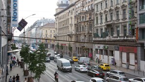A busy urban street with historic buildings, a Novotel hotel sign, and a tram line.
