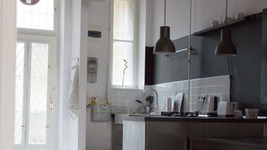 A modern kitchen with pendant lighting, a wooden floor, and a view to the living area.