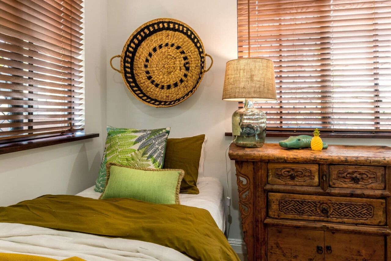 Une chambre à coucher avec un lit, des oreillers, une décoration murale, une lampe et une commode en bois.