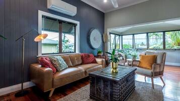 A living room with a leather sofa, a coffee table, a chair, and a large window.