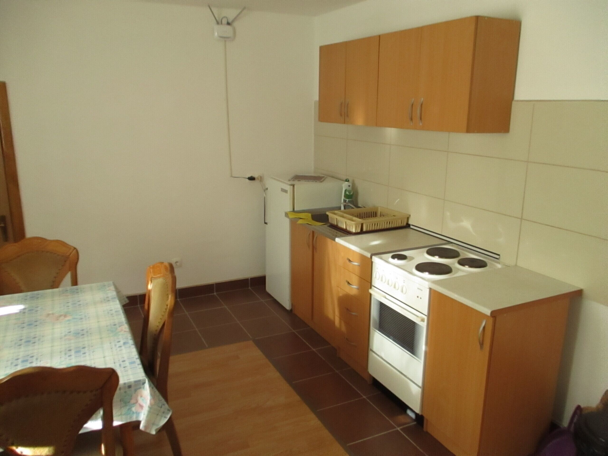 Una cucina compatta con mobili in legno, un piano cottura e un piccolo frigorifero.