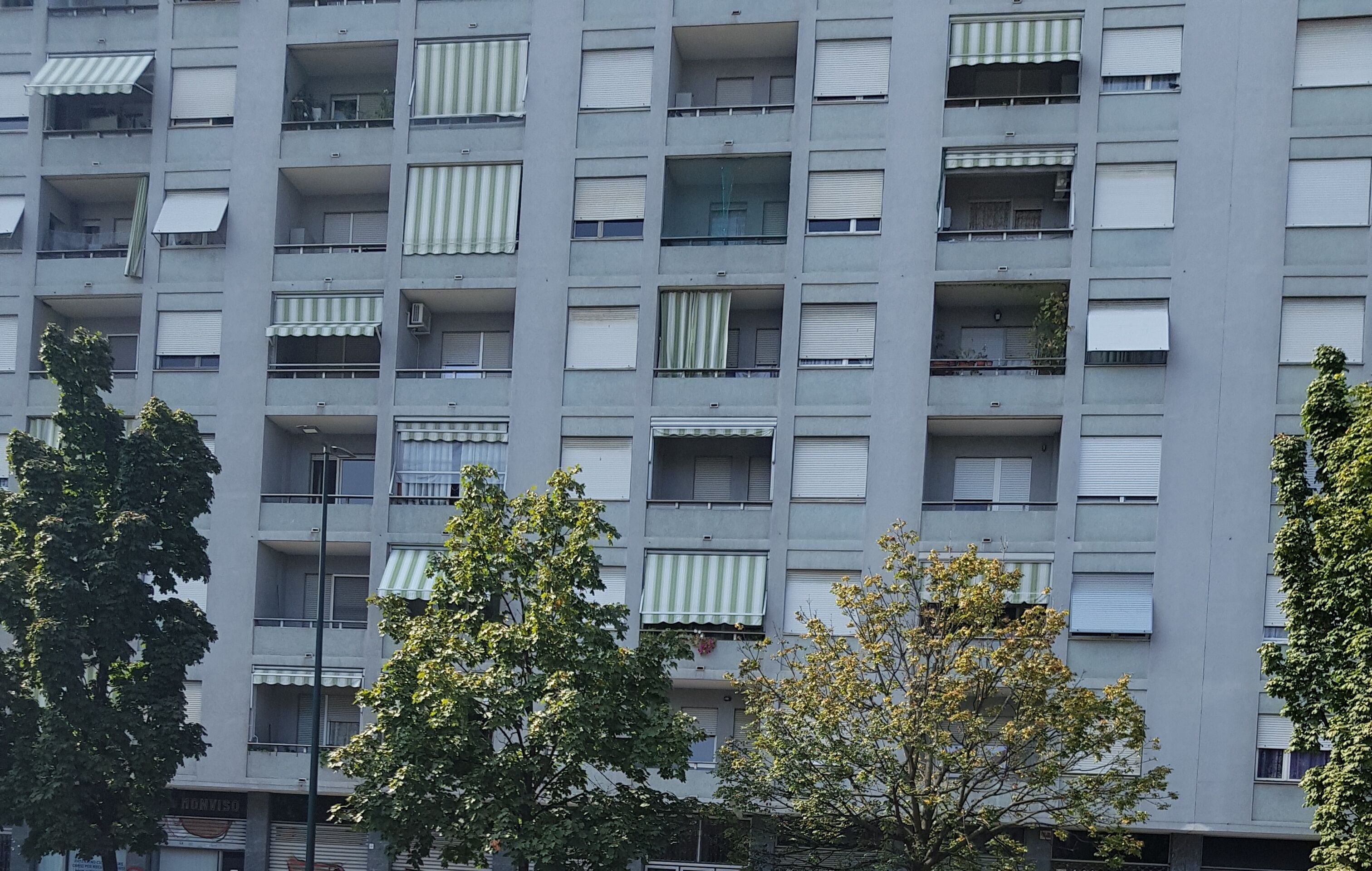 Un immeuble résidentiel à plusieurs étages, doté de balcons, dont certains sont équipés d’auvents.