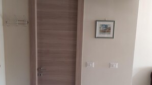 A room with a wooden door, a framed picture on the wall, and a light switch. - BRIGHT APARTMENT LINGOTTO FIERE - OLYMPIC STADIUM (Torino)