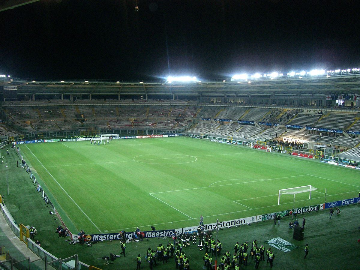 Un grand stade vide, doté d’un terrain de football en excellent état, et entouré de panneaux publicitaires.