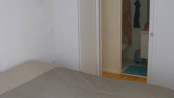 Une chambre à coucher avec un lit, une porte donnant sur une salle de bain et une petite table avec une lampe.