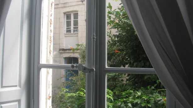 A window with a view of a building and greenery outside. - Quite apartment on garden, ideally located in the heart of La Rochelle (La Rochelle)