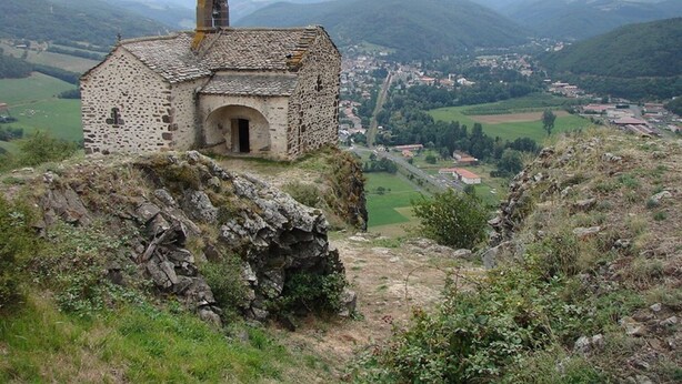 Un bâtiment en pierre, doté d’une petite entrée et d’une cheminée, entouré d’un paysage montagneux et surplombant une vallée.