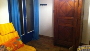 Une pièce avec une armoire en bois, un canapé agrémenté d’un coussin coloré et une nappe à motifs.