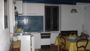 Une cuisine compacte avec une fenêtre, une table à manger avec des chaises et une petite table avec un panier.