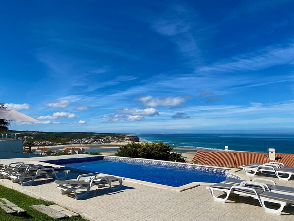 Un espace piscine avec des chaises longues et vue sur la mer.