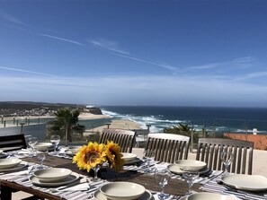 Une table dressée pour le dîner, avec vue sur l’océan et la plage.