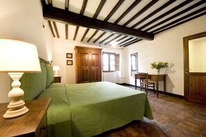 Un dormitorio con cama, escritorio, silla, lámpara y armario de madera.