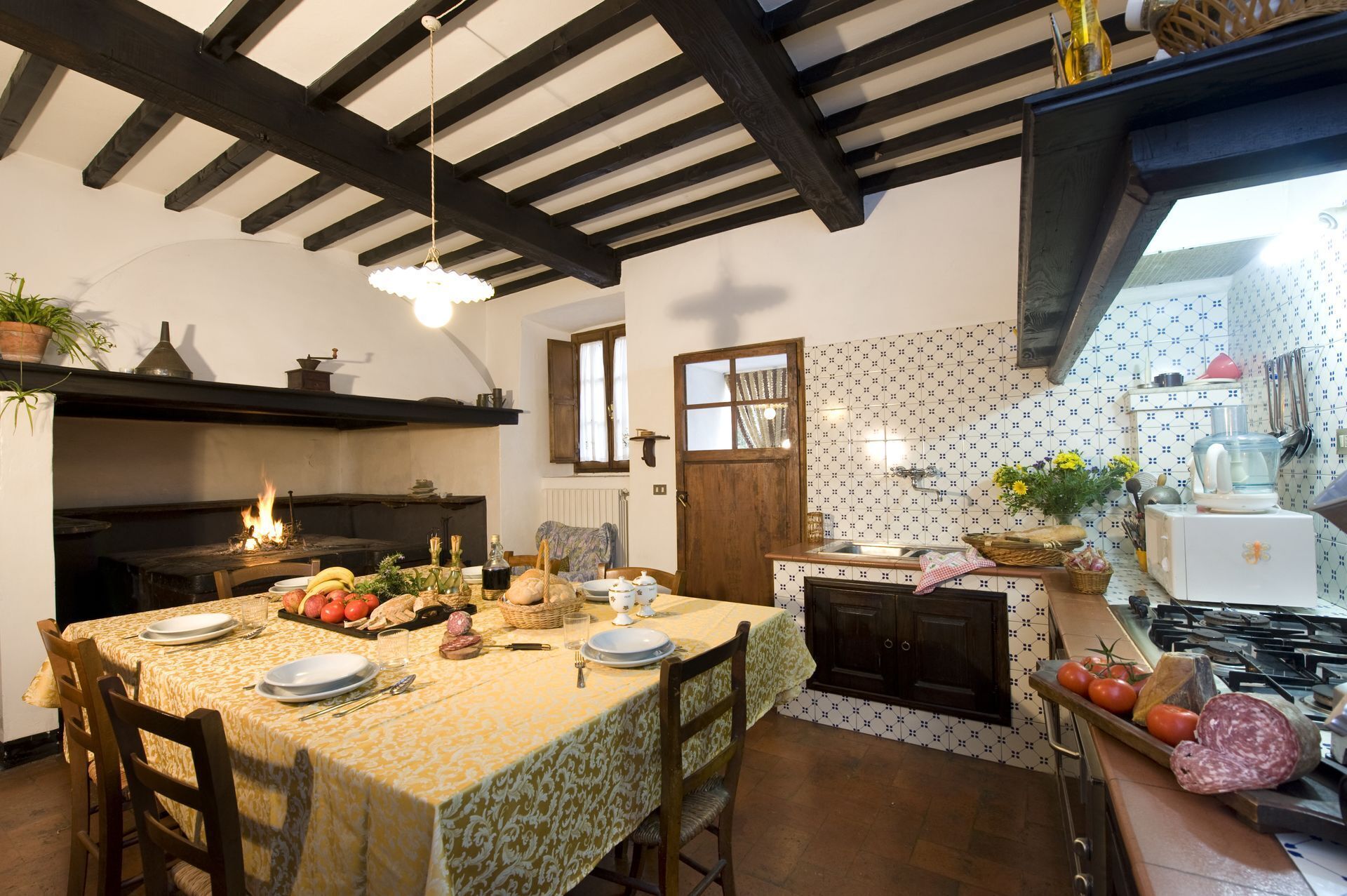 A rustic kitchen with a dining table set for a meal, a stove, and a tiled backsplash.