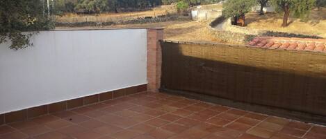 A terrace with a tiled floor, a white wall, and a brick wall.