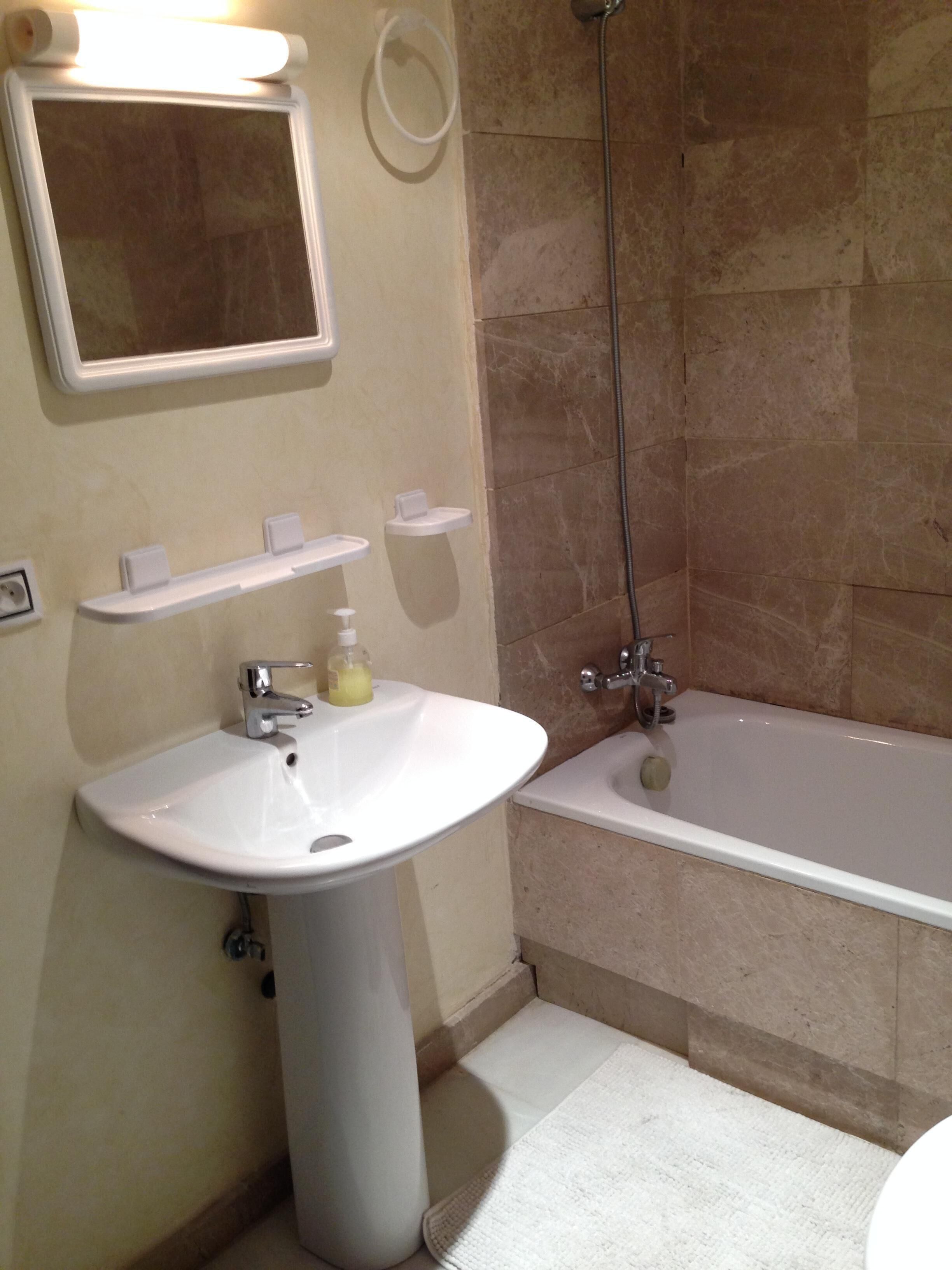 Un bagno con un lavandino bianco, uno specchio, una doccia e una vasca da bagno.