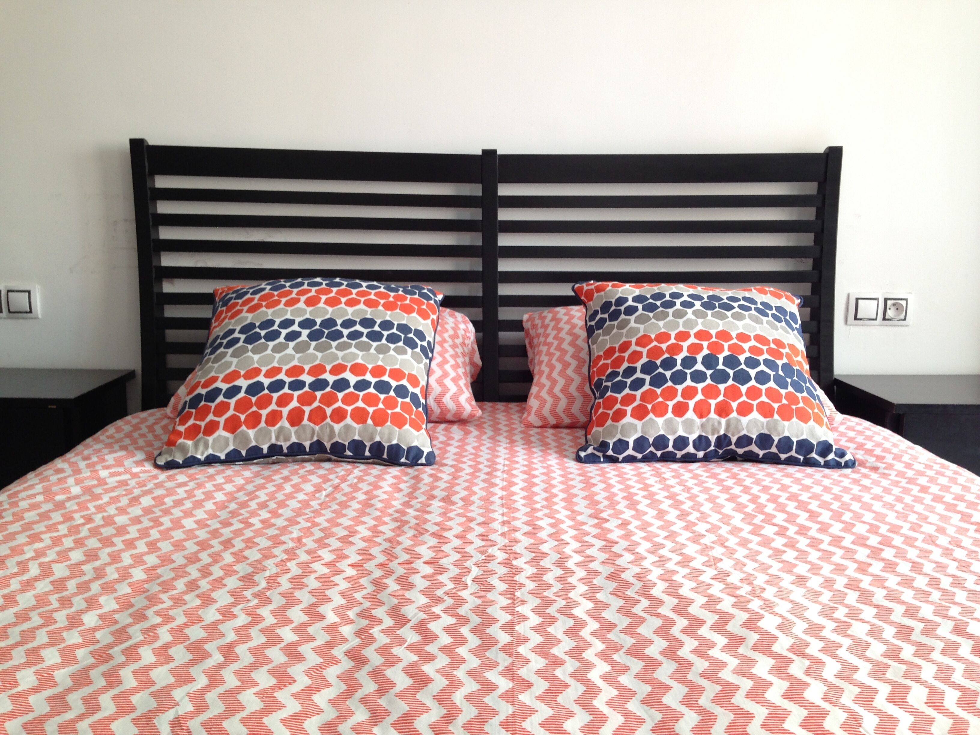 Una cama con una colcha estampada y dos almohadas decorativas.